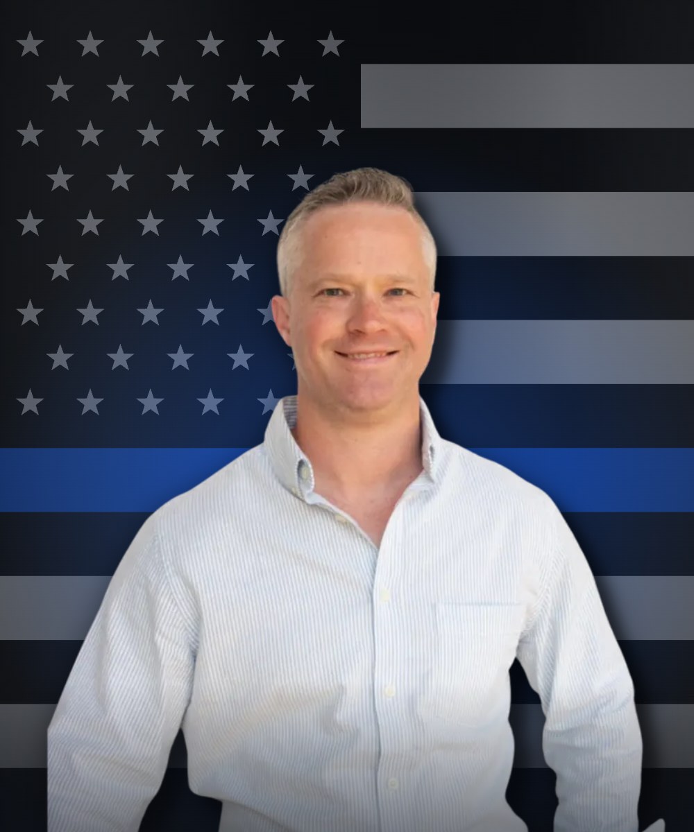 Chris Horrell, Upstate SC REALTOR and retired law enforcement officer, in front of a thin blue line flag